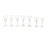 six verres à vin transparents alignés sur une surface blanche