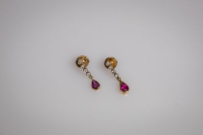 une paire de boucles d'oreilles roses et dorées posées sur un fond blanc