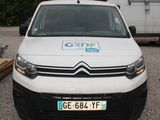 une camionnette blanche garée sur un parking, avec une remorque en arrière-plan