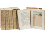 un livre ouvert posé sur une table, à côté d'une boîte remplie de livres