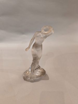 une figurine en verre représentant une femme tenant un frisbee