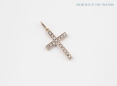 un gros plan d'un pendentif en forme de croix posé sur une surface blanche