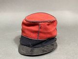 un chapeau rouge et noir posé sur une surface grise