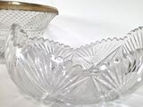 two glass bowls sitting on a table with a gold lid