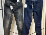deux paires de jeans suspendues à un portant dans un magasin de vêtements