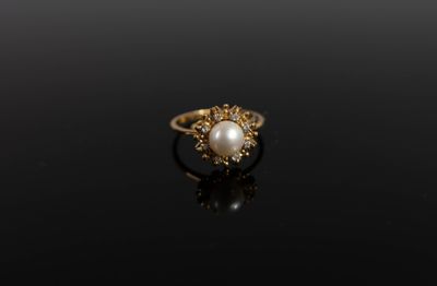 une image représentant une bague en or sertie d'une perle, sur un fond noir