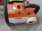 an orange and white chainsaw sitting on top of a cement floor