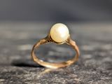 an image of a gold ring with a white pearl on it