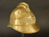 gold plated helmet on a stand with a black background