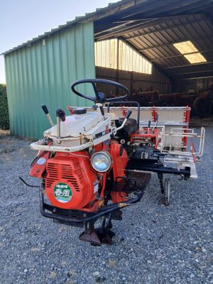 un petit tracteur rouge garé devant un bâtiment
