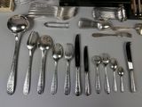 a lot of silverware on a table with a knife, fork, spoon, and spoon rest