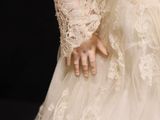 a close up of a woman ' s wedding dress with a ring on her finger