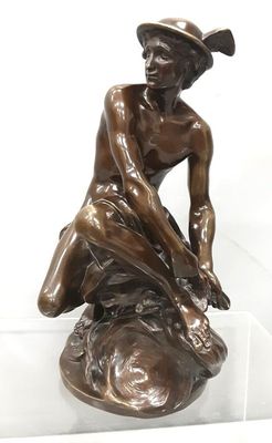 statue en bronze représentant un garçon assis sur un rocher, coiffé d'un chapeau