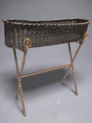 un panier en osier posé sur un support, sur fond gris