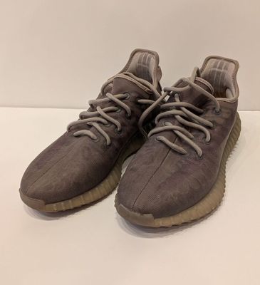 une paire de baskets grises posées sur une surface blanche