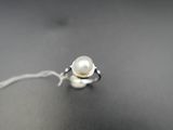 bague en argent ornée d'une perle blanche sur un fond noir