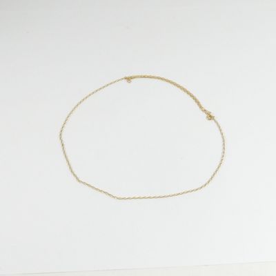 un bracelet en chaîne dorée orné d'une petite breloque en forme d'étoile sur un fond blanc