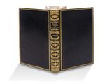 un vieux livre à la couverture noire, rehaussée de dorures sur fond blanc