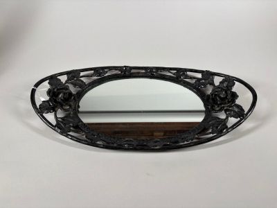 an oval shaped mirror with a black frame and flowers on it