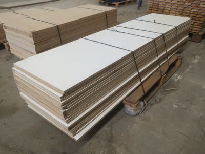 de nombreuses piles de tableaux blancs sur une palette dans un entrepôt