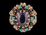 un gros plan d'une bague ornée d'une pierre violette entourée de pierres turquoise