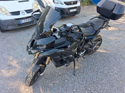 a black motorcycle parked in a parking lot next to a white van
