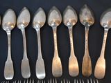 six spoons and six forks lined up on a table