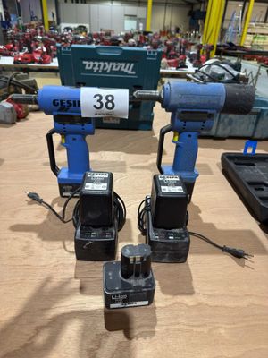 two electric drillers sitting on top of a wooden table in a workshop