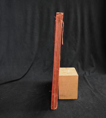 an old red book sitting on top of a wooden block