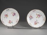 une paire d'assiettes en porcelaine ornées de motifs floraux, posées sur un présentoir