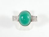 gros plan d'une bague avec une pierre verte et des diamants