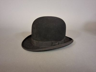 un chapeau noir orné d'un nœud, posé sur une table