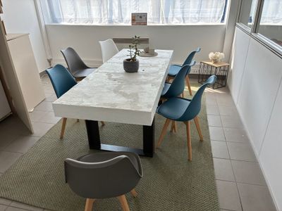 une table blanche avec des chaises bleues et une plante posée dessus
