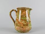 a brown and green vase with a handle on a table