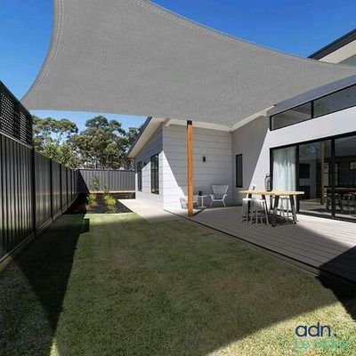 une photo d'un jardin avec une voile d'ombrage au-dessus de la terrasse
