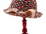 un petit chapeau posé sur un support en bois, sur fond blanc