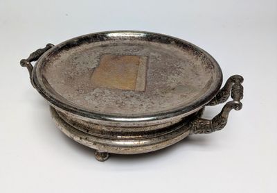 une assiette en argent ornée d'un oiseau sur un fond blanc
