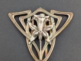 un gros plan d'une broche en métal ornée d'une fleur
