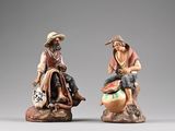 two figurines of a man and a woman sitting on a rock