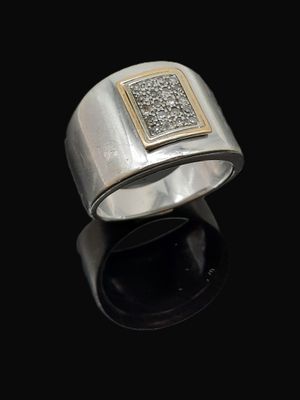 un gros plan d'une bague en argent et en or sur une surface noire