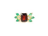 a close up of a ring with green and red stones