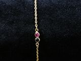 un bracelet en or avec une pierre rose et une chaîne
