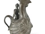 a small statue of a woman sitting on top of a bird shaped vase
