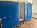 several blue lockers in a room with a red chair