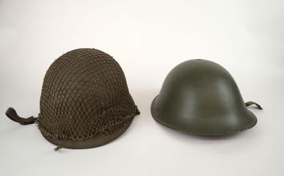 two military helmets sitting next to each other on a white surface