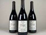 trois bouteilles de vin rouge sont posées sur une surface blanche
