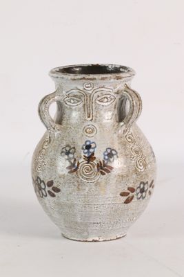 un vase blanc avec des fleurs sur une surface blanche