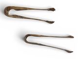 two old metal tonges are sitting on a white surface