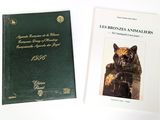 two books on a white table with a green cover and a black cat
