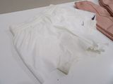 a white shirt and a pair of pink underwear on a bed